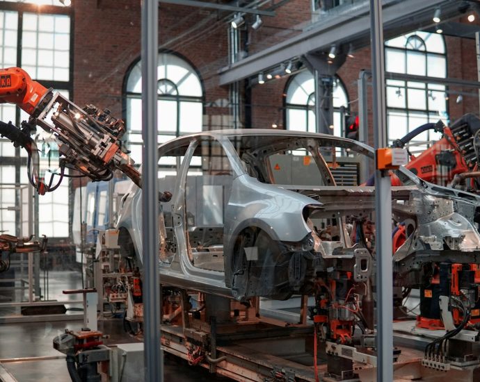 gray vehicle being fixed inside factory using robot machines
