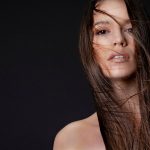 A woman poses with windblown hair.