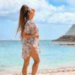 woman in white and red floral dress standing on beach during daytime