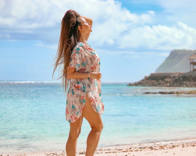 woman in white and red floral dress standing on beach during daytime