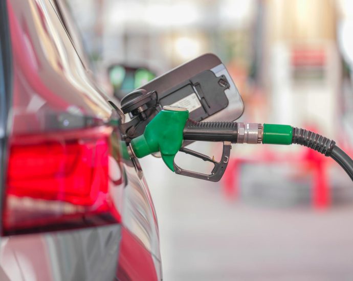 A close-up view of a fuel pump nozzle inserted into a car's tank at a gas station.