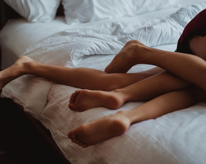 A close-up of intertwined legs illustrating intimacy and relaxation on a bed.