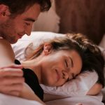 Intimate moment of a couple cuddling in bed, showcasing warmth and affection.
