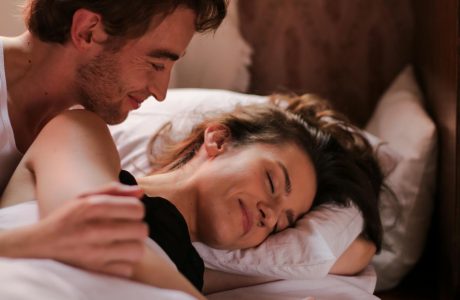 Intimate moment of a couple cuddling in bed, showcasing warmth and affection.