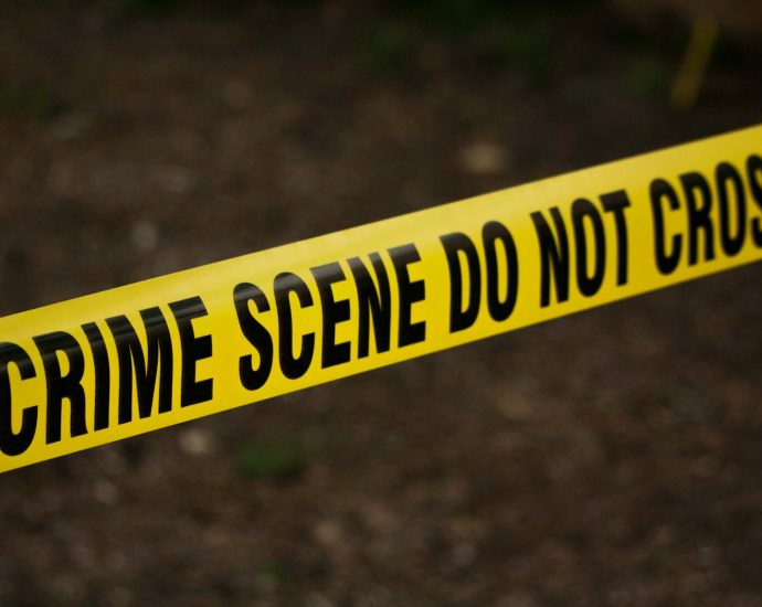 Close-up of crime scene tape with 'Do Not Cross' text, outdoors setting.