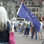 A woman walking down a street holding a flag