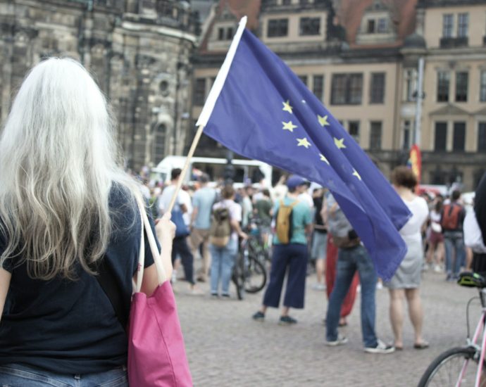 A woman walking down a street holding a flag