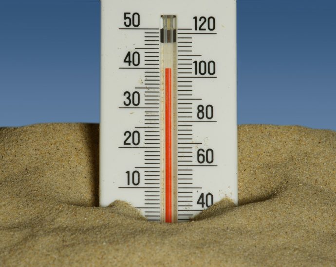 A thermometer in the sand with a blue sky in the background