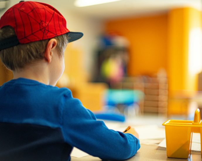 a young boy sitting at a table writing on a piece of paper