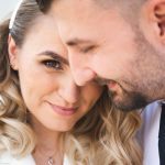 A couple embraces closely, looking at the camera