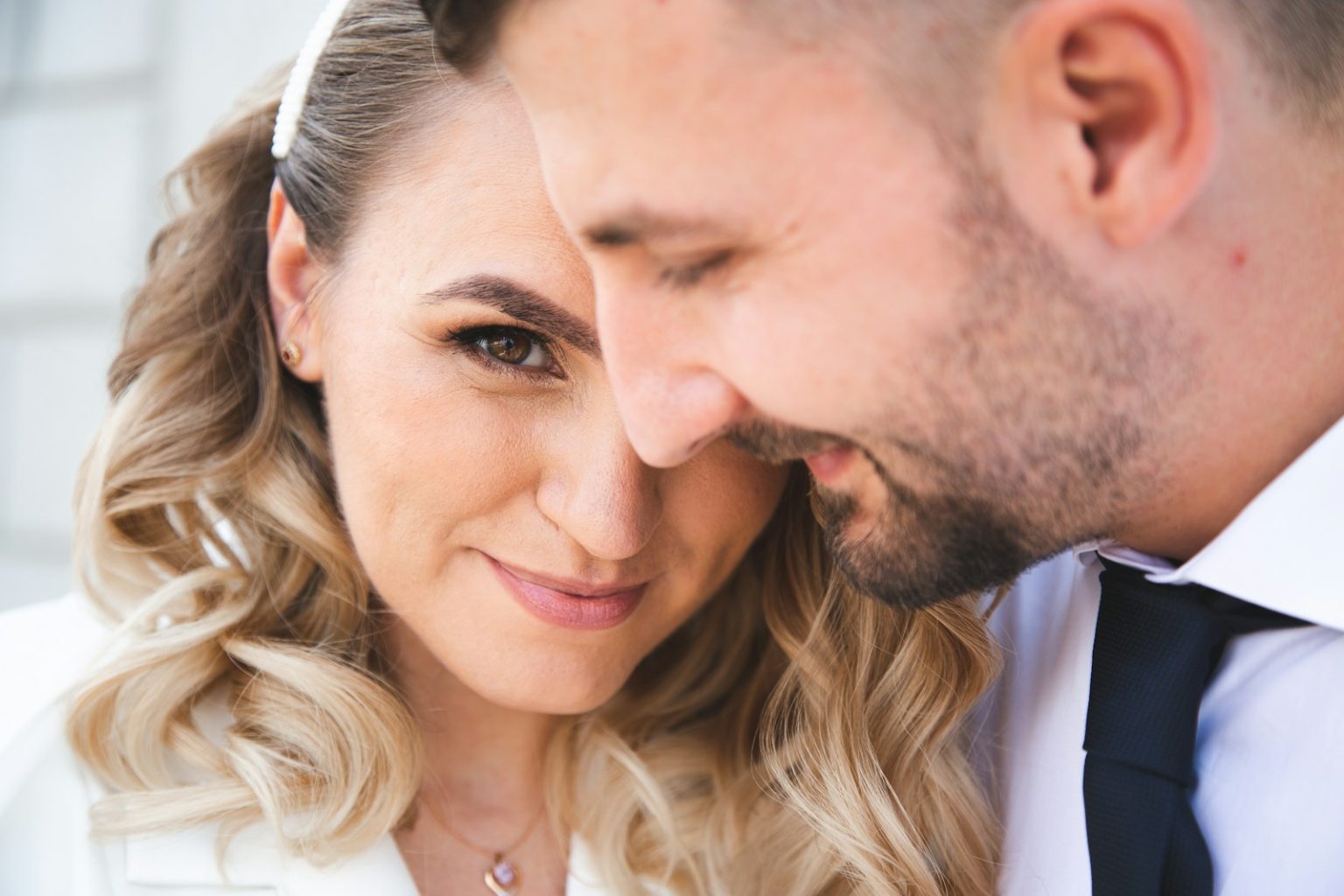 A couple embraces closely, looking at the camera