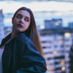 Young woman poses with a city background.
