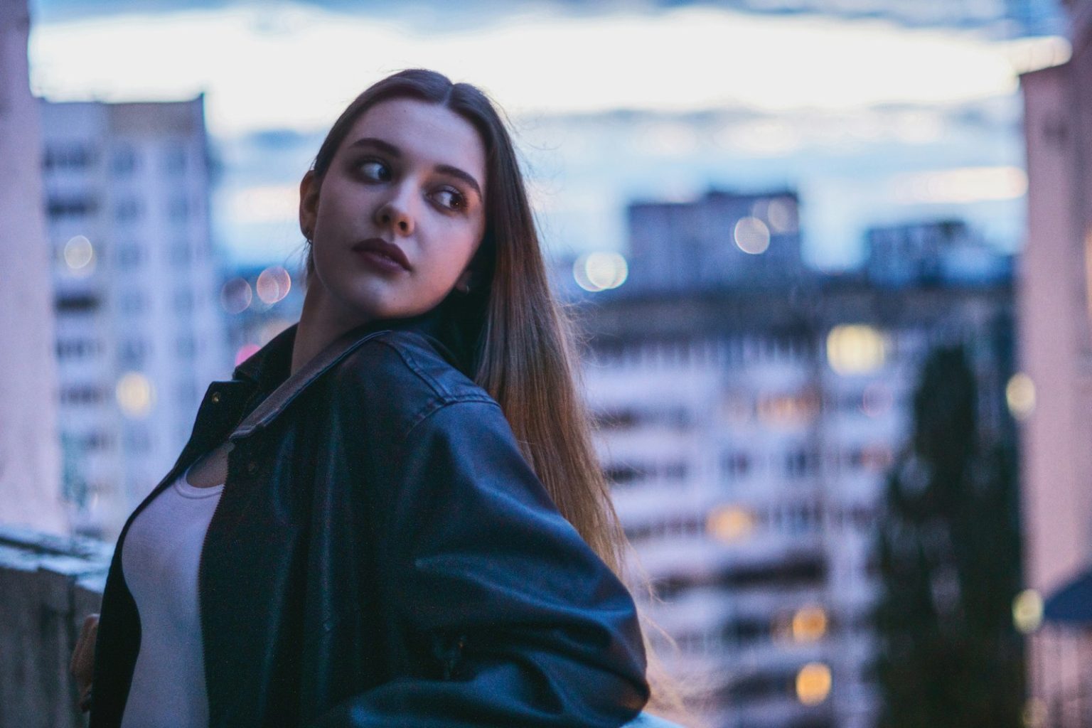 Young woman poses with a city background.