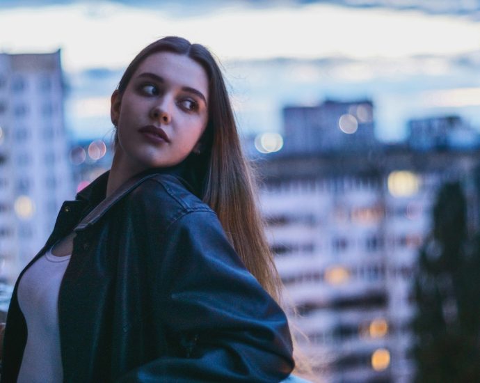 Young woman poses with a city background.