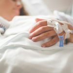 a woman laying in a hospital bed with an iv in her hand