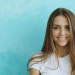 Young woman smiles against a blue textured wall