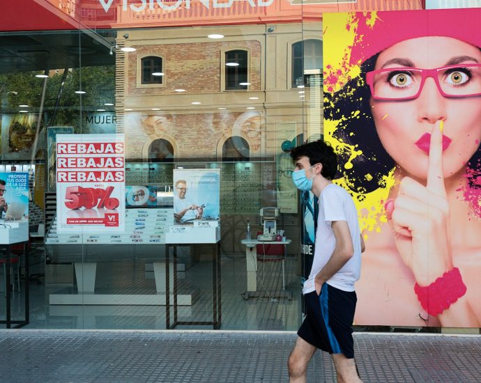 woman in white shirt and black skirt standing near glass window