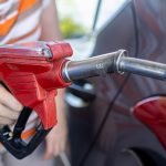 a woman filling a car with gas at a gas station