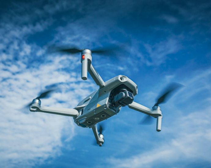 white and black drone flying under blue sky during daytime