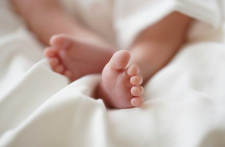babys feet on white textile