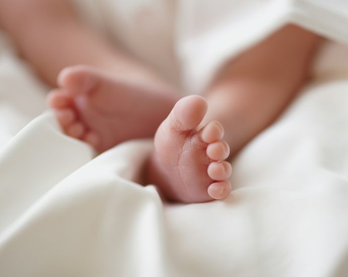 babys feet on white textile