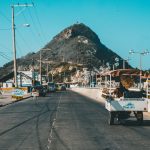 white auto rickshaw on riding on asphalt road towards green mountain