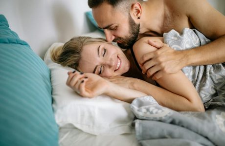 Happy couple embracing in bed, showcasing love and affection in a cozy home setting.