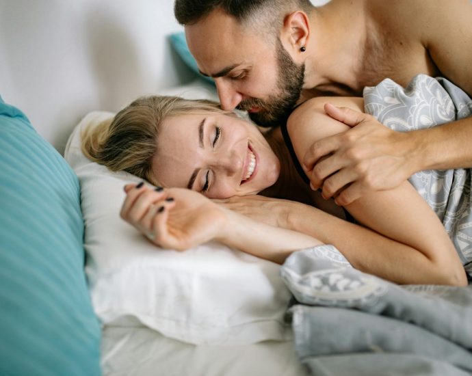 Happy couple embracing in bed, showcasing love and affection in a cozy home setting.