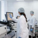 Two scientists in protective gear working with lab equipment in a high-tech laboratory.