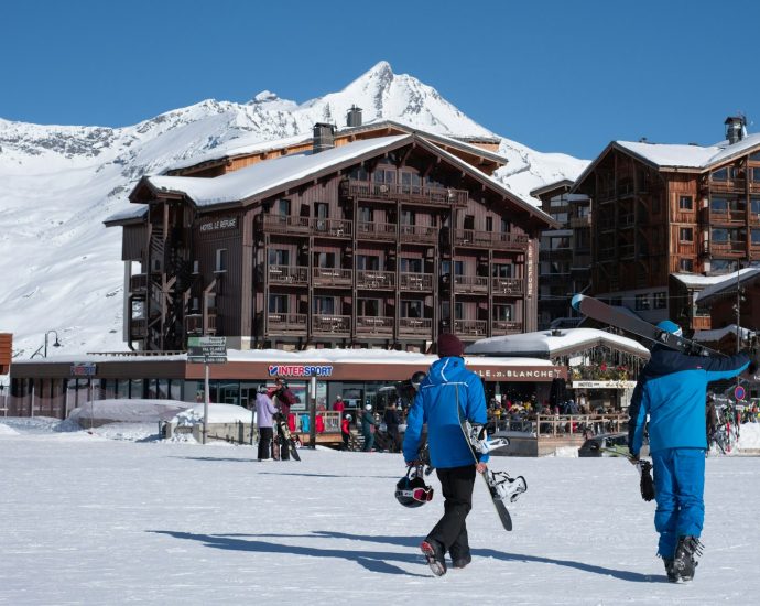 a couple of people walking across a snow covered field