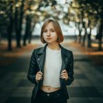 Young woman in leather jacket standing in park