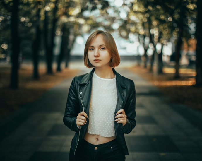Young woman in leather jacket standing in park