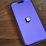 A cell phone with a purple background and a black sticker on the back of