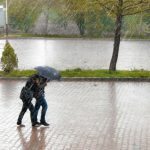 coupe walking in street while raining