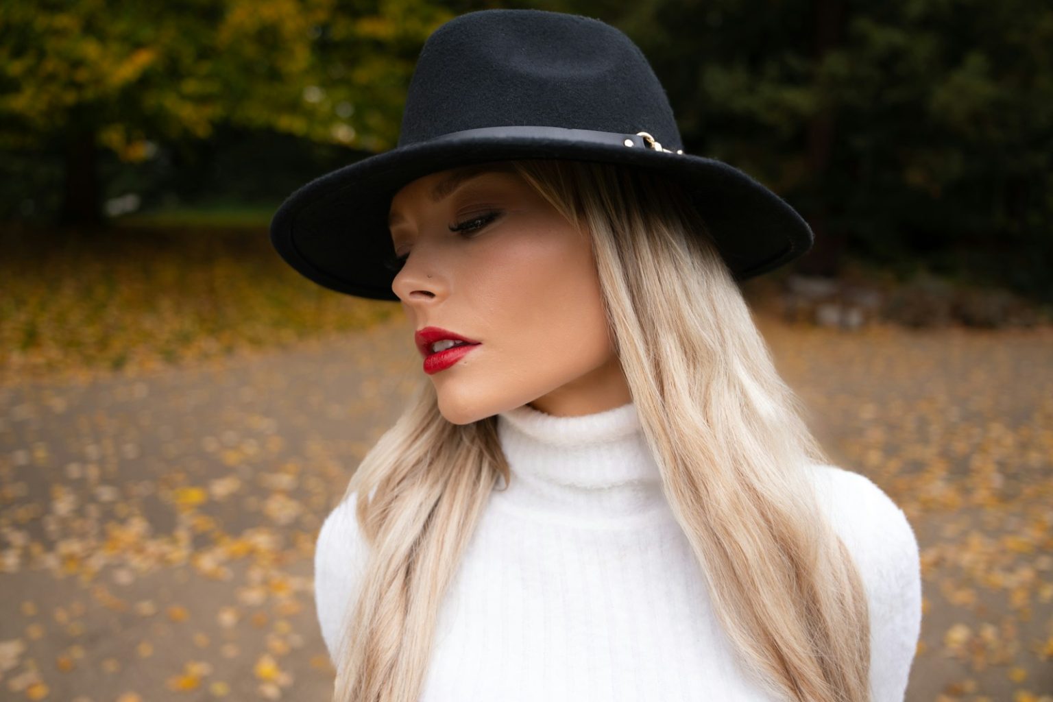 Woman wearing a black fedora and white turtleneck