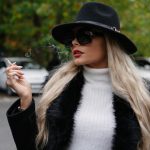 Woman in hat smoking a cigarette outdoors