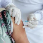 Close-up of a healthcare professional giving a vaccine shot to a patient wearing a mask.