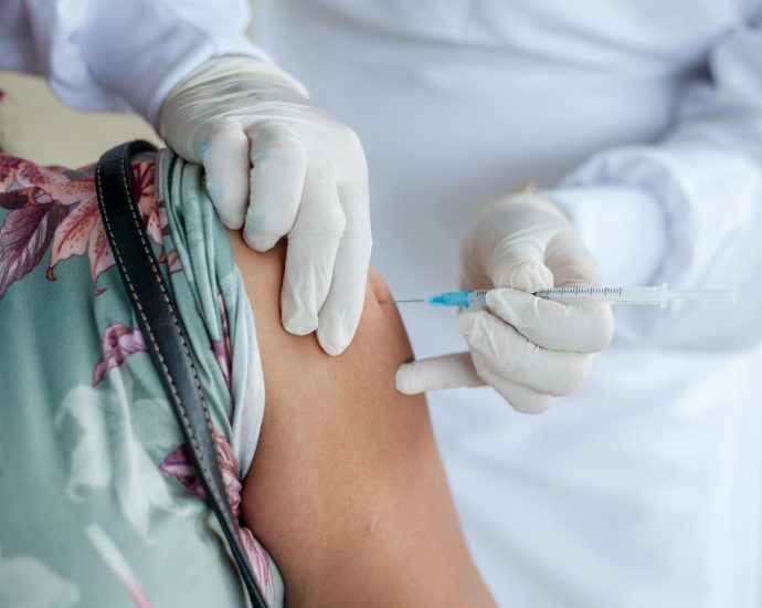 Close-up of a healthcare professional giving a vaccine shot to a patient wearing a mask.