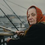 woman fishing on bridge during daytime