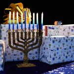 a lit menorah and gift boxes on a table