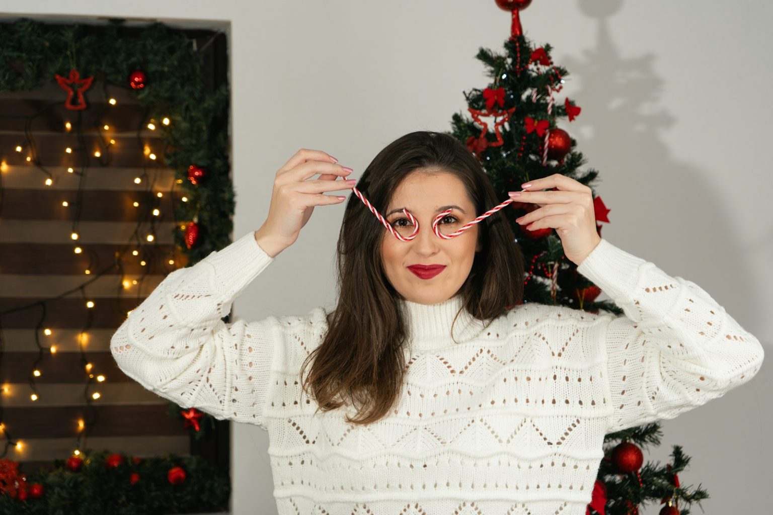 a woman holding a pair of glasses in front of a christmas tree