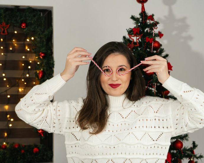 a woman holding a pair of glasses in front of a christmas tree