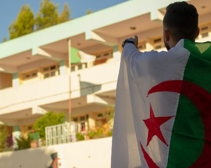 man in white shirt standing near white concrete building during daytime