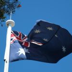 A flag flying high in the sky next to a tree