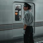 man in black hat standing in front of white train