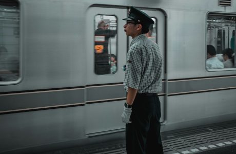 man in black hat standing in front of white train