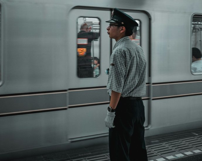 man in black hat standing in front of white train