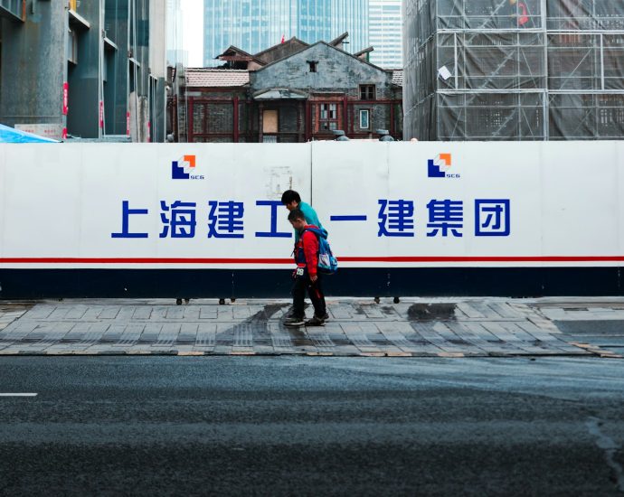 A woman crossing a street in front of a large billboard