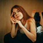 Young woman with red hair lying on a chair