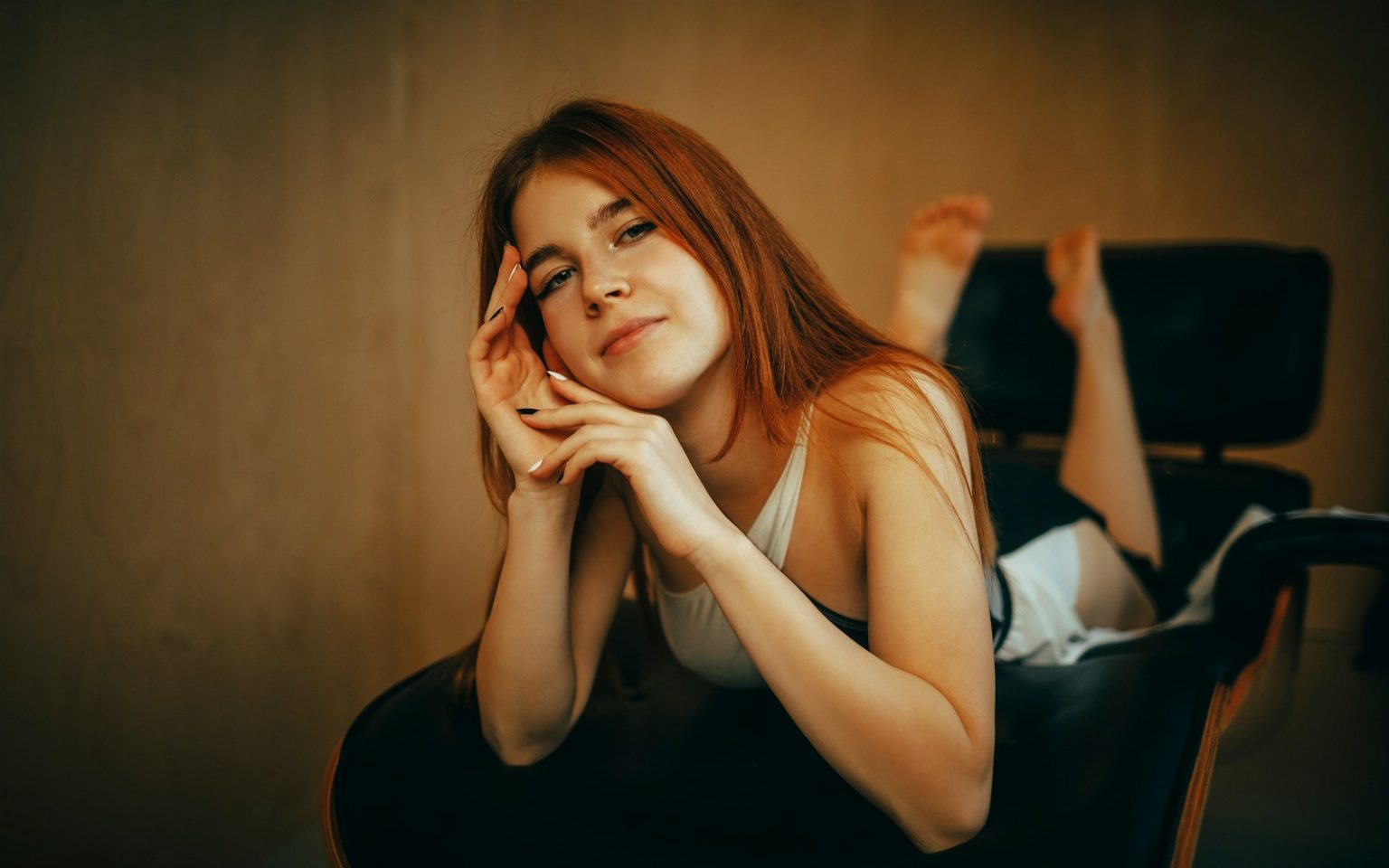 Young woman with red hair lying on a chair
